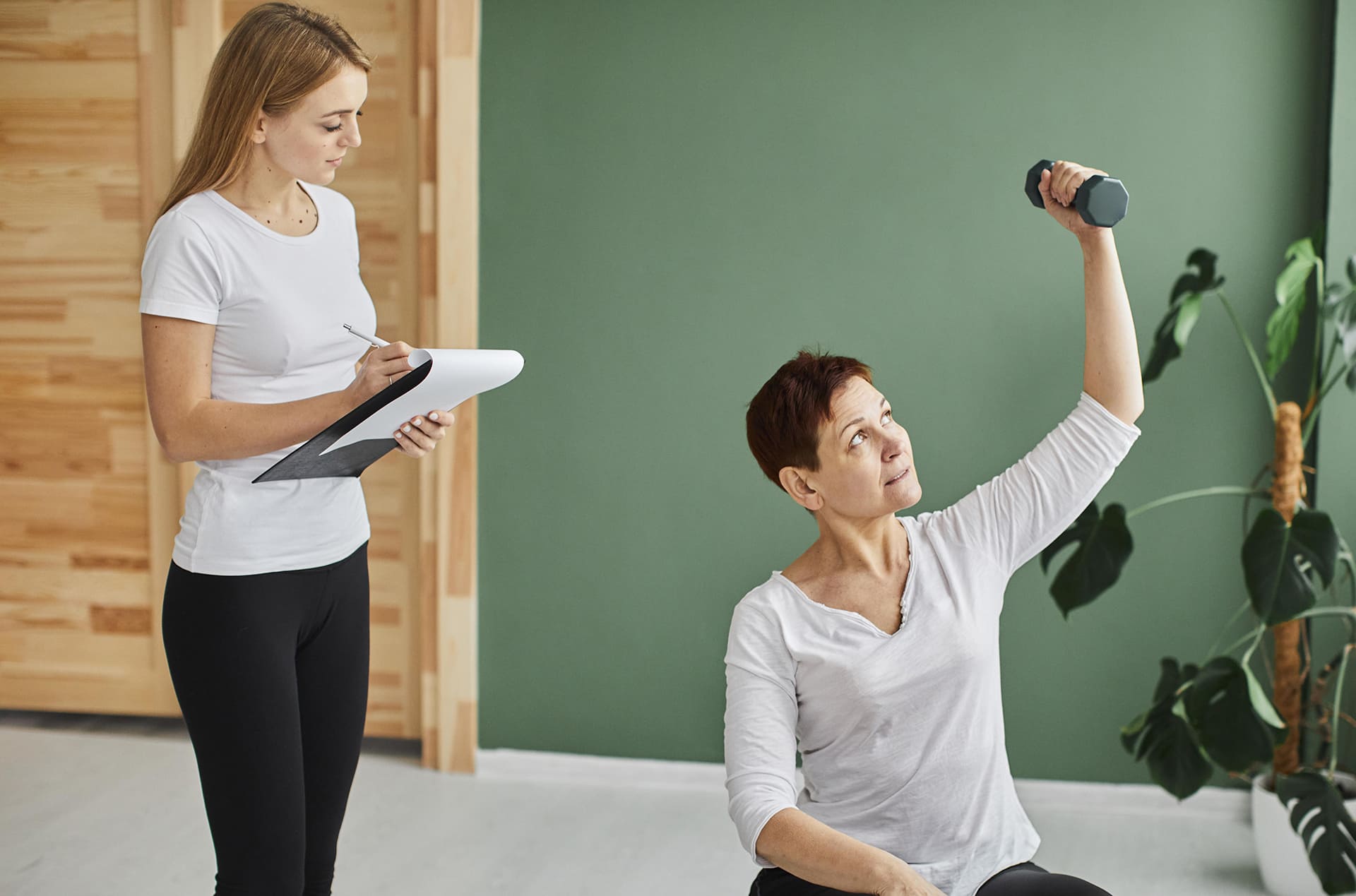 front-view-elder-woman-covid-recovery-doing-physical-exercises-with-dumbbell-while-nurse-checks